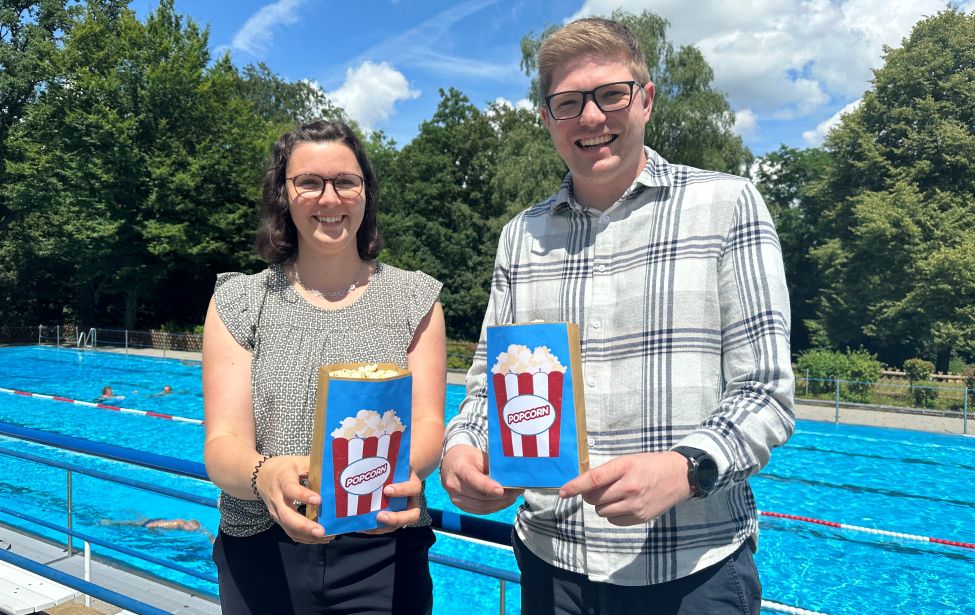 Svenja Breddemann, Klimaschutzmanagerin und Niels Vogel, Leiter Referat Sport und Bewegung bewerben das Open-Air-Kino Ende August im Freibad.
